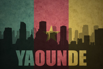 abstract silhouette of the city with text Yaounde at the vintage cameroon flag