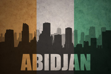 abstract silhouette of the city with text Abidjan at the vintage ivorian flag