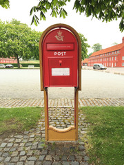 Roter Briefkasten mit Aufschrift Post auf gelber St&uuml;tze
