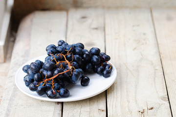 Bunch of ripe blue grapes on a light wooden background
