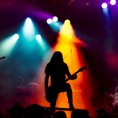 Plakat silhouette of guitar player in action on stage in front of concert crowd