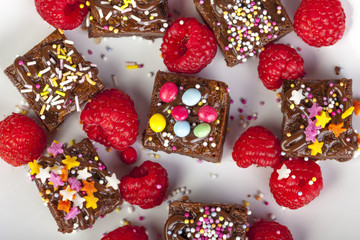 Candy topped chocolate brownies and raspberries viewed from abov