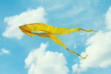 Yellow kite flying blue sky. Cloudy day summer scene. Freedom concept image