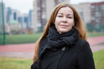 Caucasian woman portrait in black coat and scarf, long hair. Outdoor