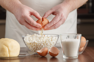 Closeup photo of man breaking egg in glass bowl