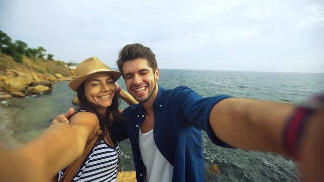 Handsome young smiling man kissing his girlfriend , while posing on a selfie picture , staying on the beach.