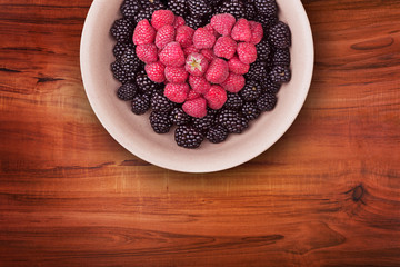Ceramic plate with heart shaped berries on the top of the wooden table with clipping path. Top view.