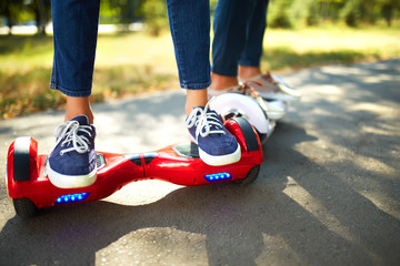 young man and woman riding on the Hoverboard in the park. content technologies. a new movement. Close Up of Dual Wheel Self Balancing Electric Skateboard Smart. on electrical scooter outdoors   © maxbelchenko