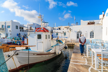Fototapeta na wymiar Old fisherman walking in port with fishing boats in Naoussa town, Paros island, Greece