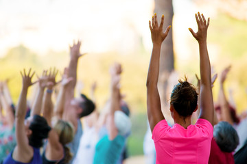 hands raised of people doing yoga in a park