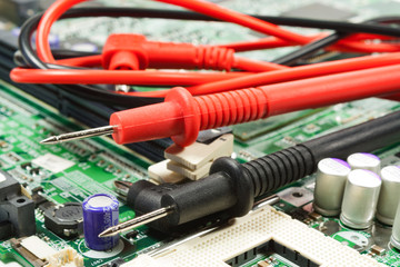Multimeter probe on the motherboard in a workshop