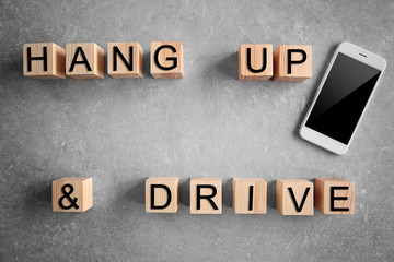 Cubes with words HANG UP AND DRIVE and smartphone on grey background, top view