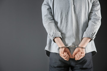 Man in handcuffs on grey background