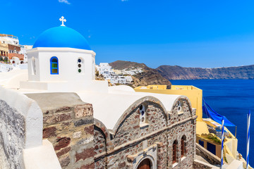 White church with blue dome in Oia village on Santorini island, Greece