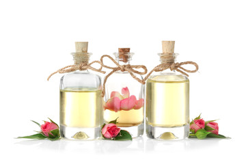Bottles of aroma oil with roses on white background