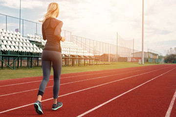 Athletic fitness fit woman running on stadium. Sport, jogging, healthy life style concept