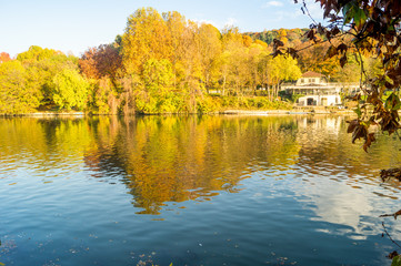 Fototapeta na wymiar Colorfull italian park with trees and autumn colors and water