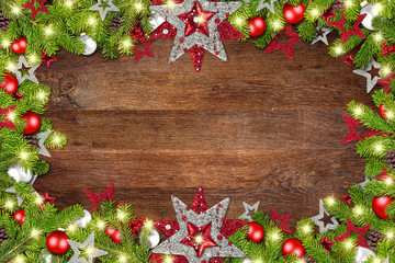 Fototapeta na wymiar xmas christmas dark wood background with decorated fir branches frame with many lights and copy space / Festlicher Weihnachten Hintergrund auf holz mit geschmückten tannenzweigen Rahmen