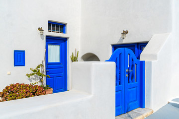 Blue gate and door of typical white Greek house in Oia village, Santorini island, Greece