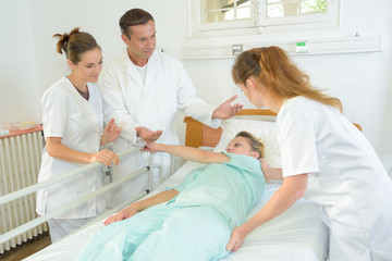 physical therapist helps patient to move in hospital bed