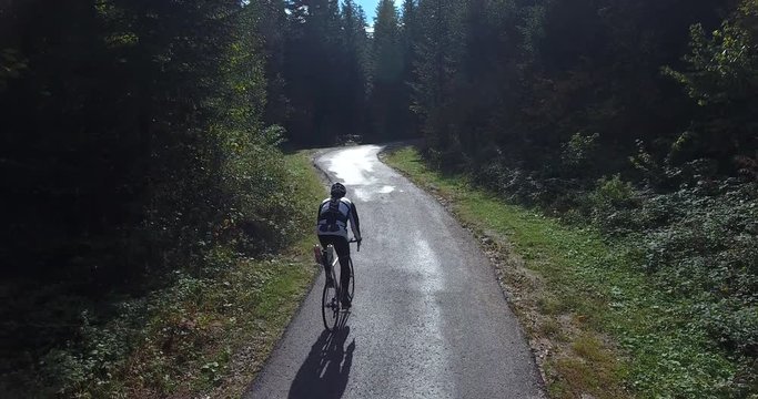 Footage of a speed cycler training, he is cicling up a road in the woods...