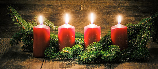 Vierter Advent: vier leuchtende Kerzen vor einem Holzhintergund - 126168211