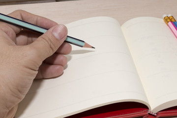 office desk with group of pencil and hand , hand write note on paper,white paper,copy space,blank paper for write note
