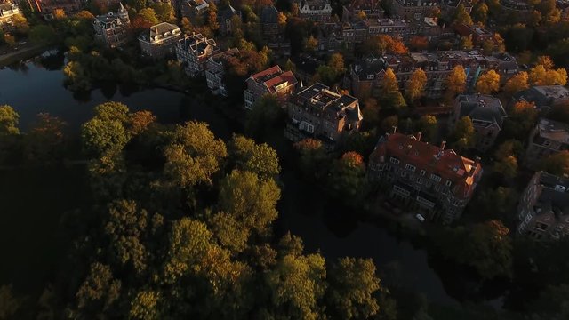 Aerial over Vondelpark and well to do neighborhood in south of Amsterdam during golden hour.