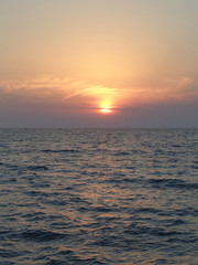 Fototapeta na wymiar Морской закат, вечернее солнце в дымке облаков