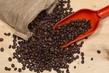 Coffee beans in an old bag and a spoon on wooden table