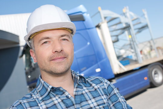Portrait of man in hardhat in front of lorry