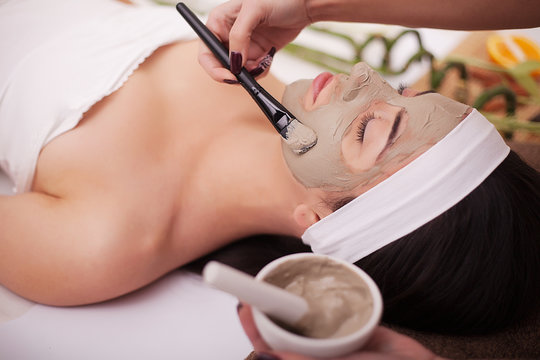 Spa therapy for young woman having facial mask at beauty salon - indoors