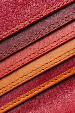 Leather samples with stitches, natural materials with seams of red, maroon, brown, orange colors and other warm shades, women bag detail, macro shot, selective focus 