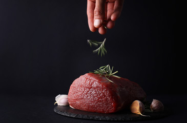 Cooking concept , man decorating raw beef meat with with rosemary close up.