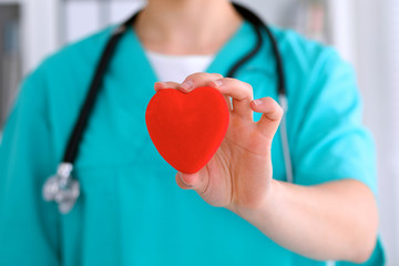 Female surgeon doctor with stethoscope holding heart.