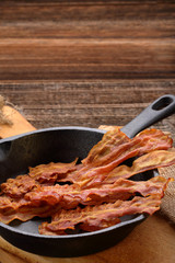 Hot fried bacon pieces in a cast iron skillet