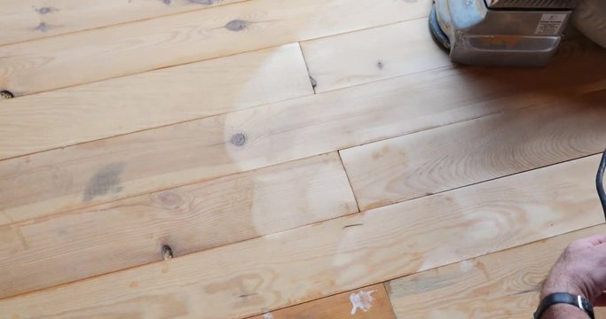 A high angle shot of a man sandering a parquet with a sandering machine...