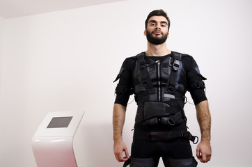 Strong , muscular man standing next to ems machine, muscle stimulation