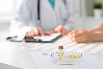 Medicine capsules and pills are lying against the background of a doctor and patient