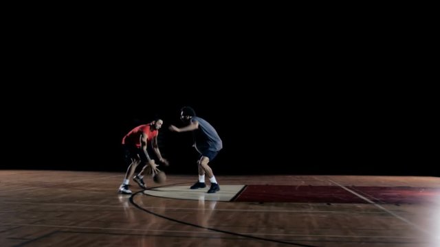 A basketball player dribbles past a defender and then dunks the ball