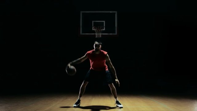 Wide shot of an isolated basketball player doing tricks with the ball 