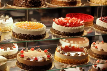 Gordijnen Verschillende soorten taarten in de glazen vitrine van de banketbakkerij © wideonet