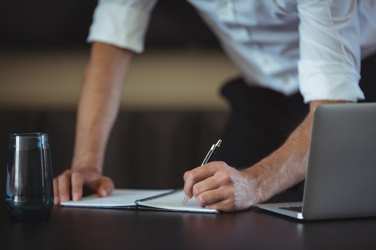 Businessman writing in notepad at desk