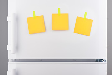 Yellow paper notes attached with stickers on white refrigerator