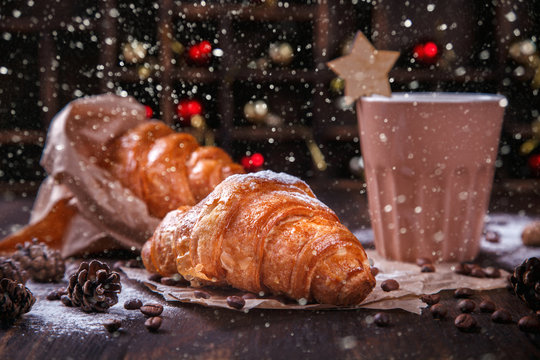  Christmas or New Year pastries,Croissant with a warming drink,coffee.Winter Holidays Concept.Holiday Decorations. top view.Toned image.Drawn Snowfal.selective focus.