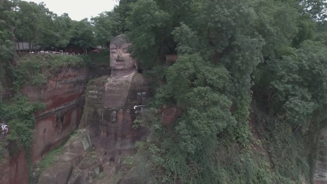 Panning aerial drone shot of the impressive giant Buddha statue in Leshan, China