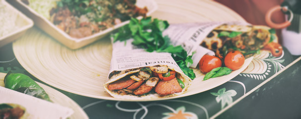 Street food sandwiches or tacos with grilled meat and vegetables. Street food or unhealthy concept, horizontal, vintage toned