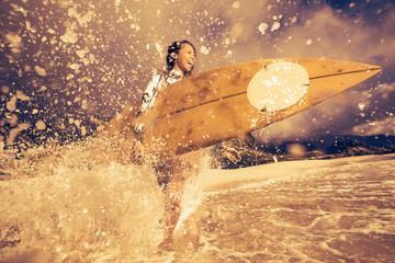 Surfing girl with surfboard in water splashes
