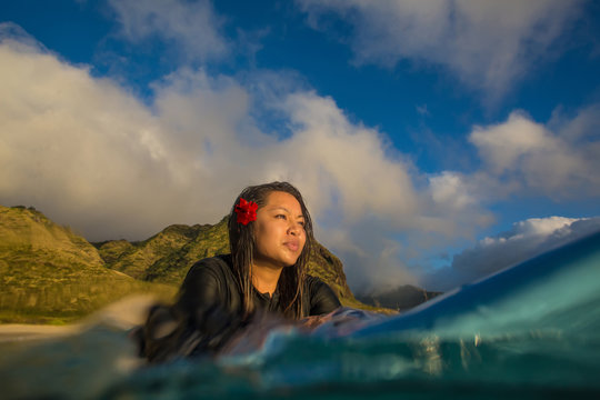 Attractive Brunette hawaiian girl on surboard in ocean water at