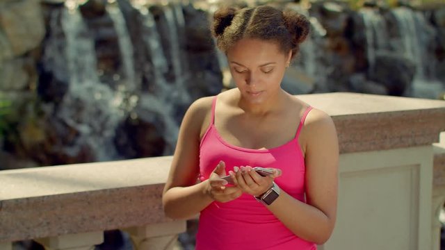 Girl watching photos on smart phone. Latin girl using phone at park. African girl looking at phone screen. Girl phone. Girl using smartphone. Digital life. Modern lifestyle. Girl using mobile phone
